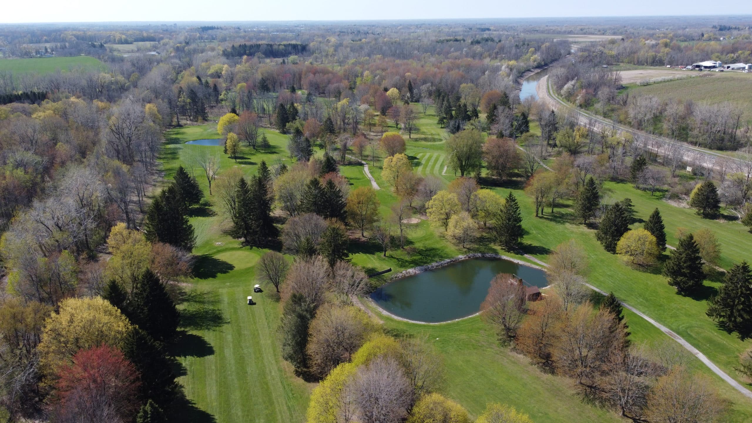 golf course with pond and trees, aerial view. A serene landscape with greenery.