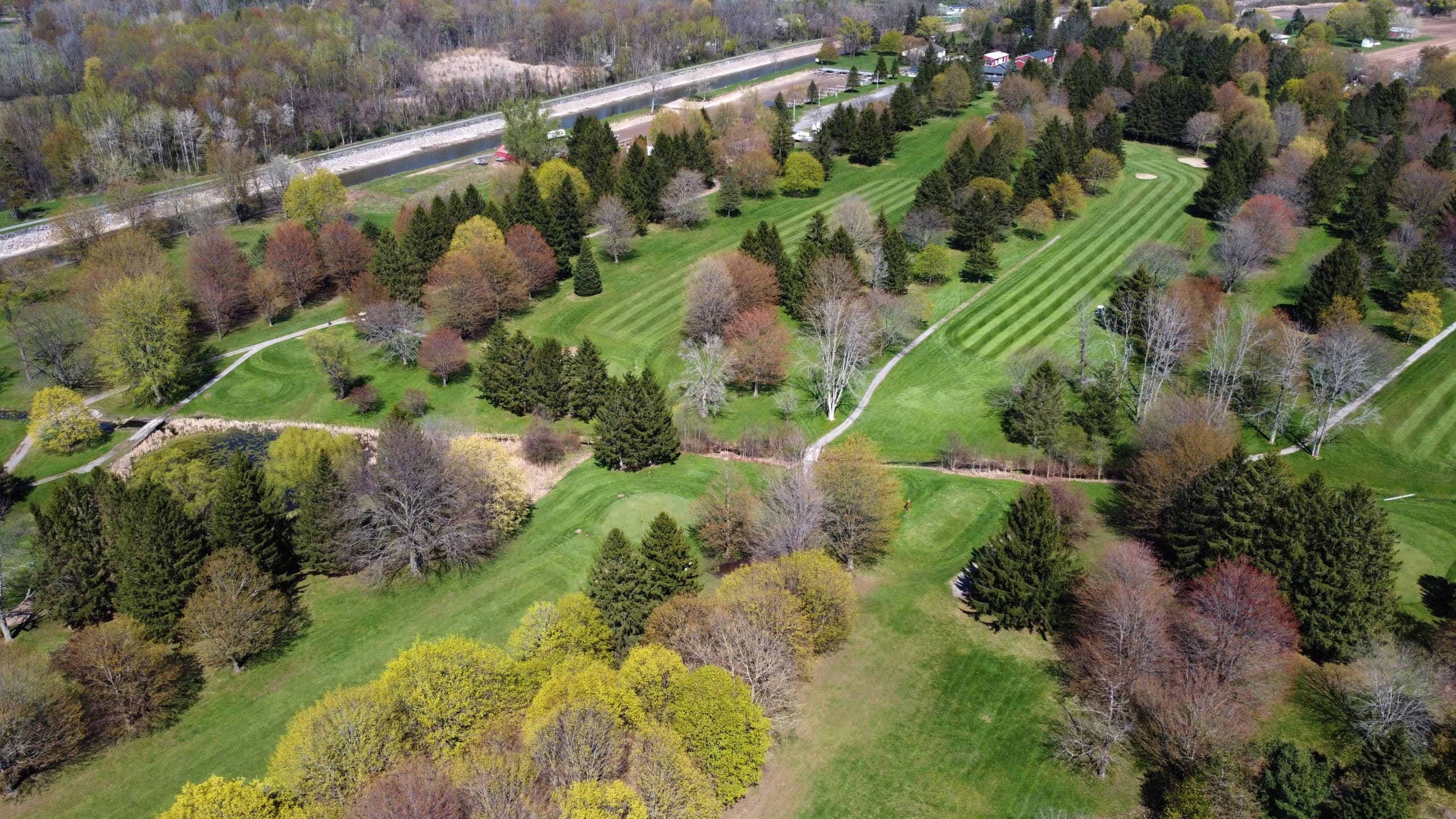 Golf course with trees and roads. Aerial view of green grassy landscape.